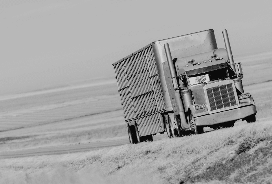 a semi truck driving on a highway through a field